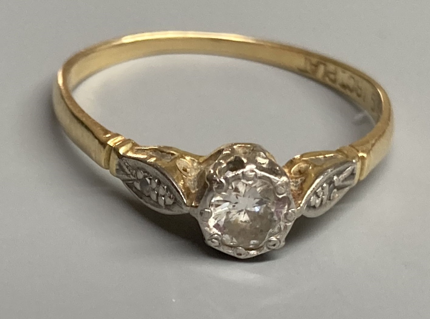An 18ct & plat, single stone diamond ring, with diamond set shoulders, size P, gross 1.9 grams.